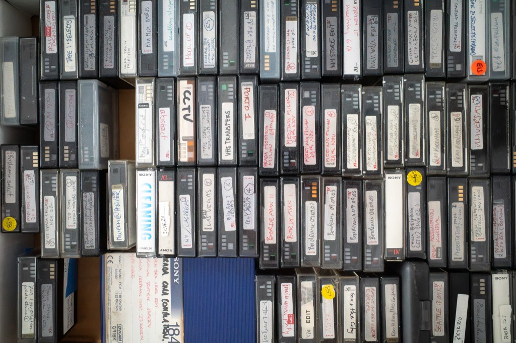 The physical MiniDV and DVCAM archive, tapes packed in a drawer with handwritten labels.